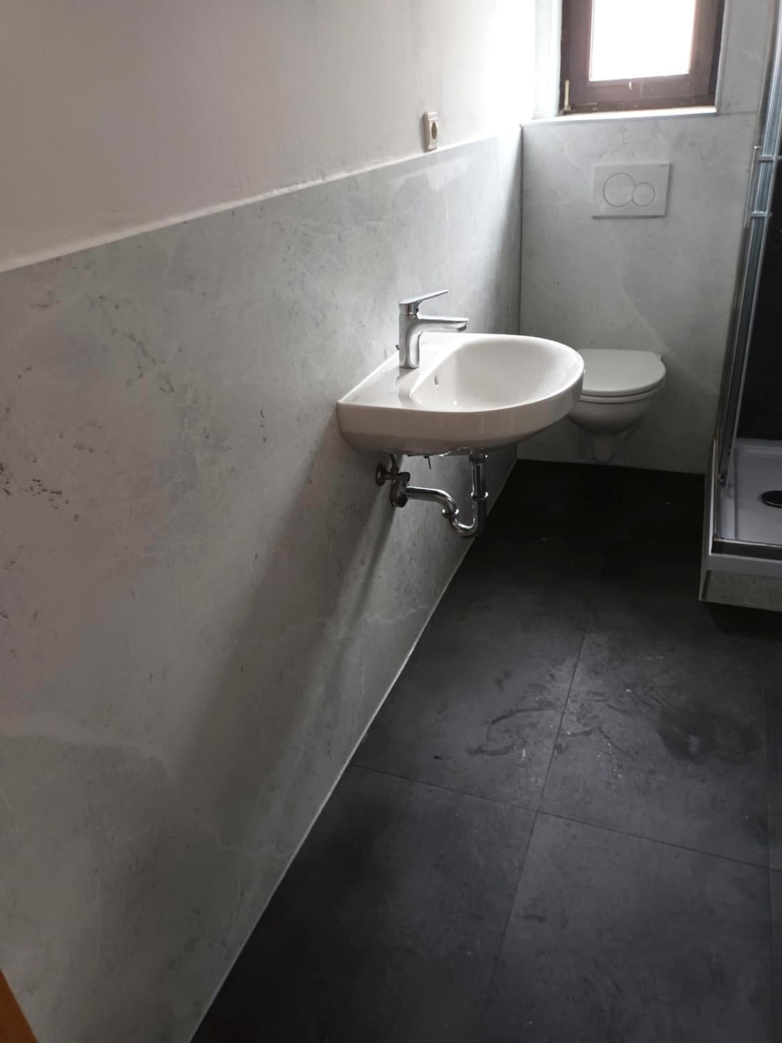 Fugenlose Badezimmerwand mit Waschbecken und WC